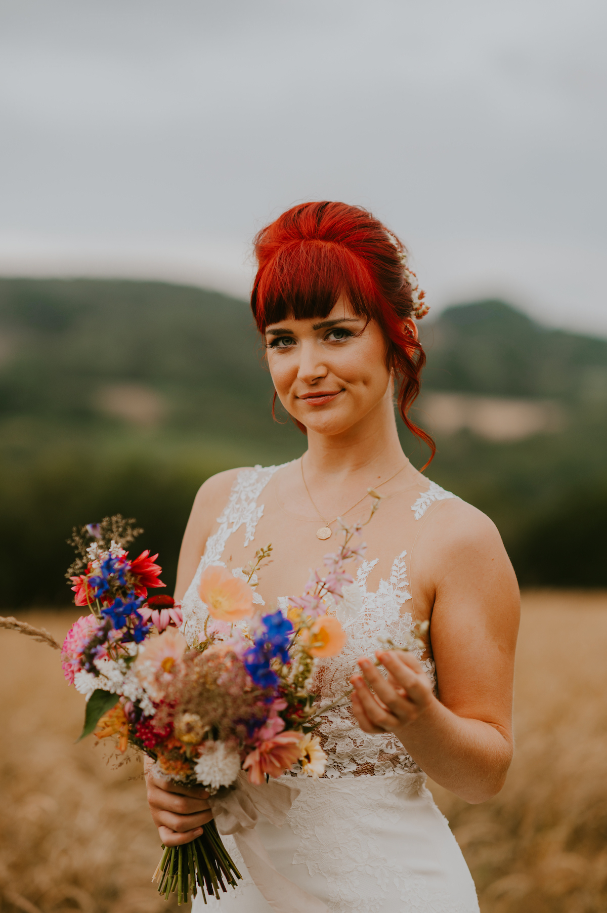 Bride holding bouquet against the backdrop of the meadows at River Cottage